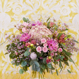 Bouquet de fleurs au style champêtre et vaporeux dans les tons rosés avec des touches de vert.