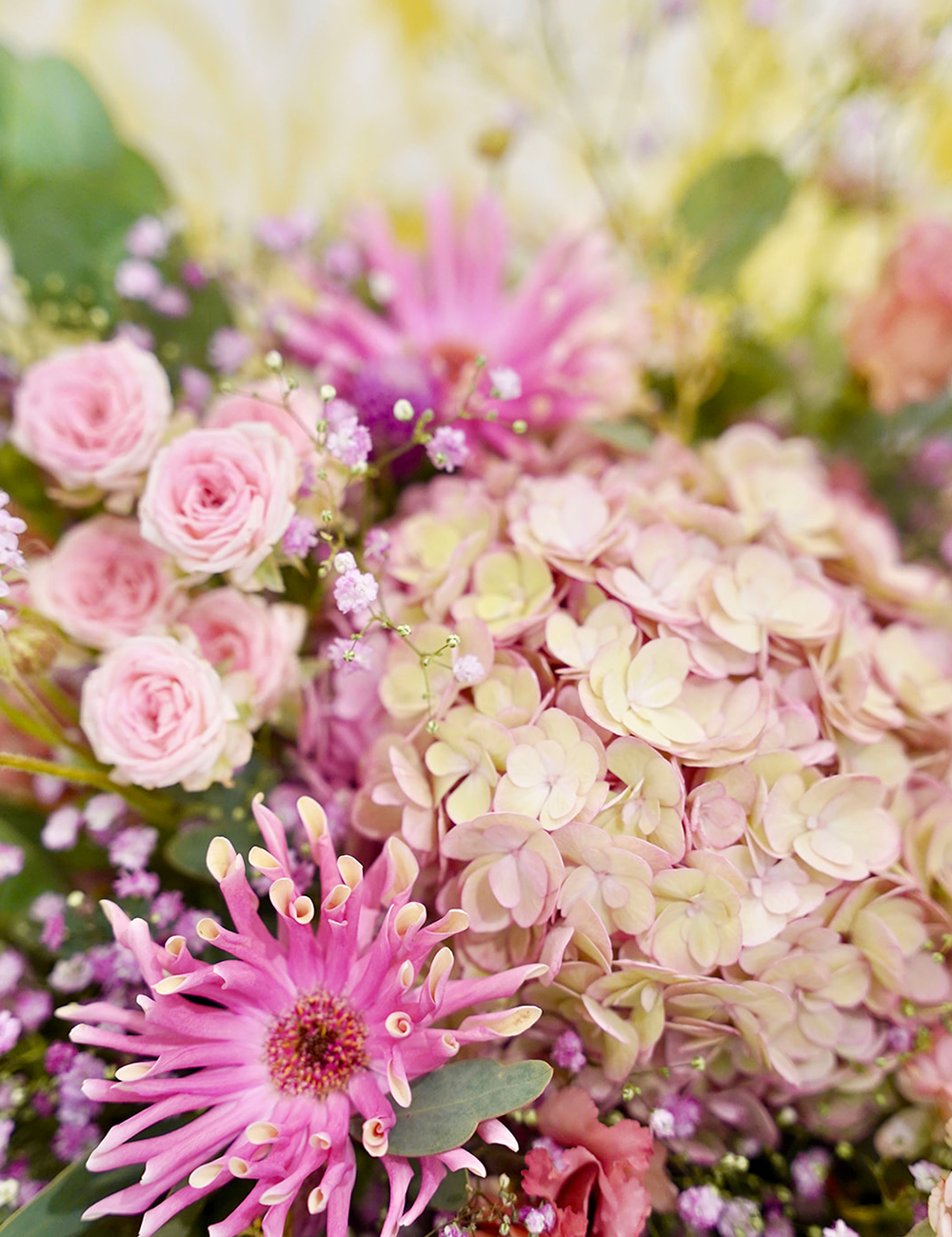Zoom sur un bouquet de fleurs au style champêtre et vaporeux dans les tons rosés avec des touches de vert.