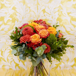 Bouquet de fleurs rond dans les tons rouges et oranges avec des touches de vert.
