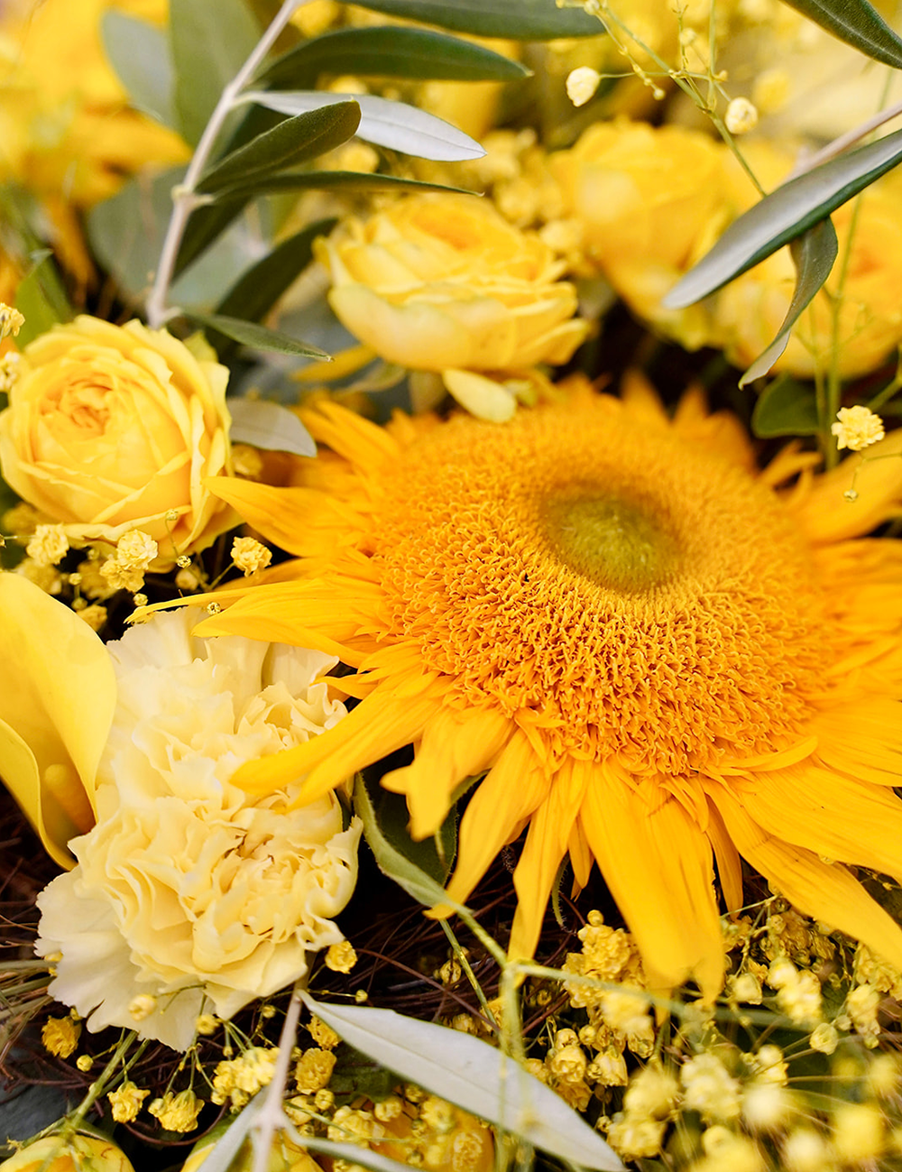 Zoom sur un bouquet de fleurs au style champêtre et vaporeux dans les tons jaunes avec des touches de vert.v