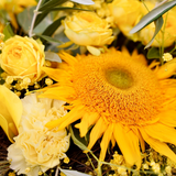 Zoom sur un bouquet de fleurs au style champêtre et vaporeux dans les tons jaunes avec des touches de vert.v