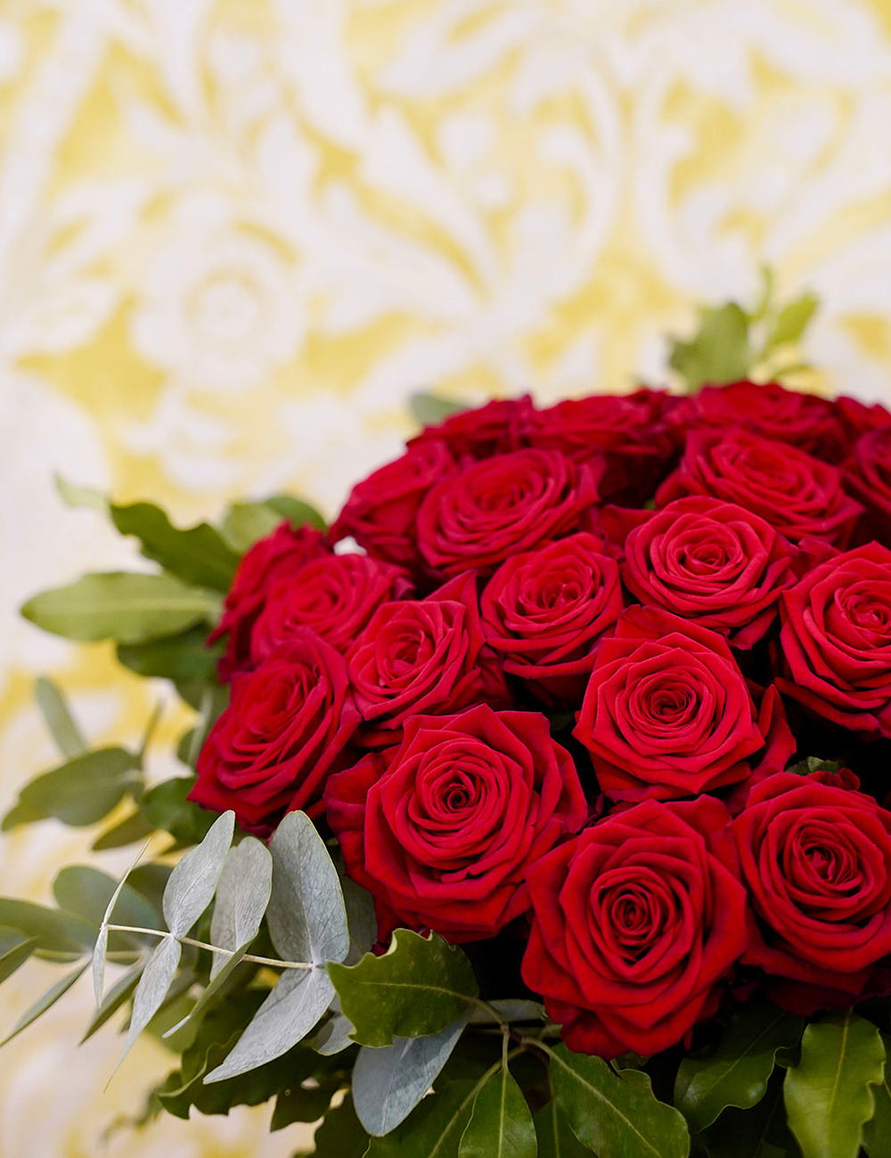 Zoom sur un bouquet de roses dans les tons rouges avec des touches de vert.