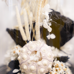 Zoom sur une composition de fleurs séchées sous cloche aux tons noirs décoration automne