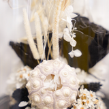 Zoom sur une composition de fleurs séchées sous cloche aux tons noirs décoration automne