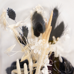 Zoom sur une composition de fleurs séchées sous cloche aux tons noirs décoration automne